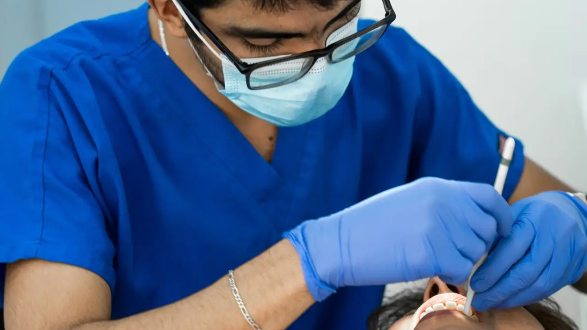 a man in a blue shirt is getting his teeth checked